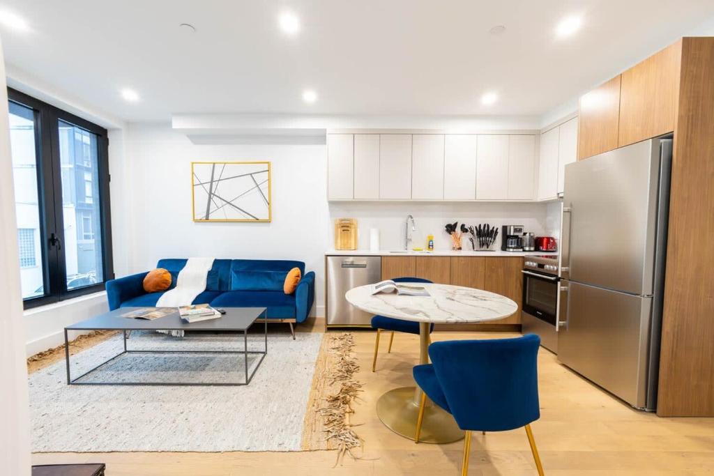 a kitchen and living room with a blue couch and a table at 202 New Condo 1BR in Prime Greenpoint in Brooklyn