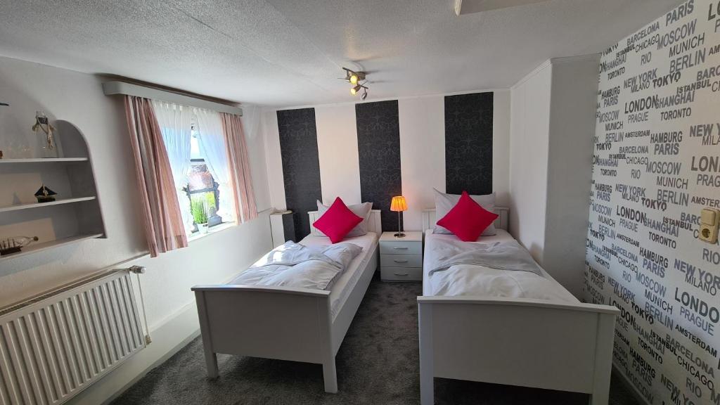 two beds in a small room with red pillows at Appartement 24 in Kappeln
