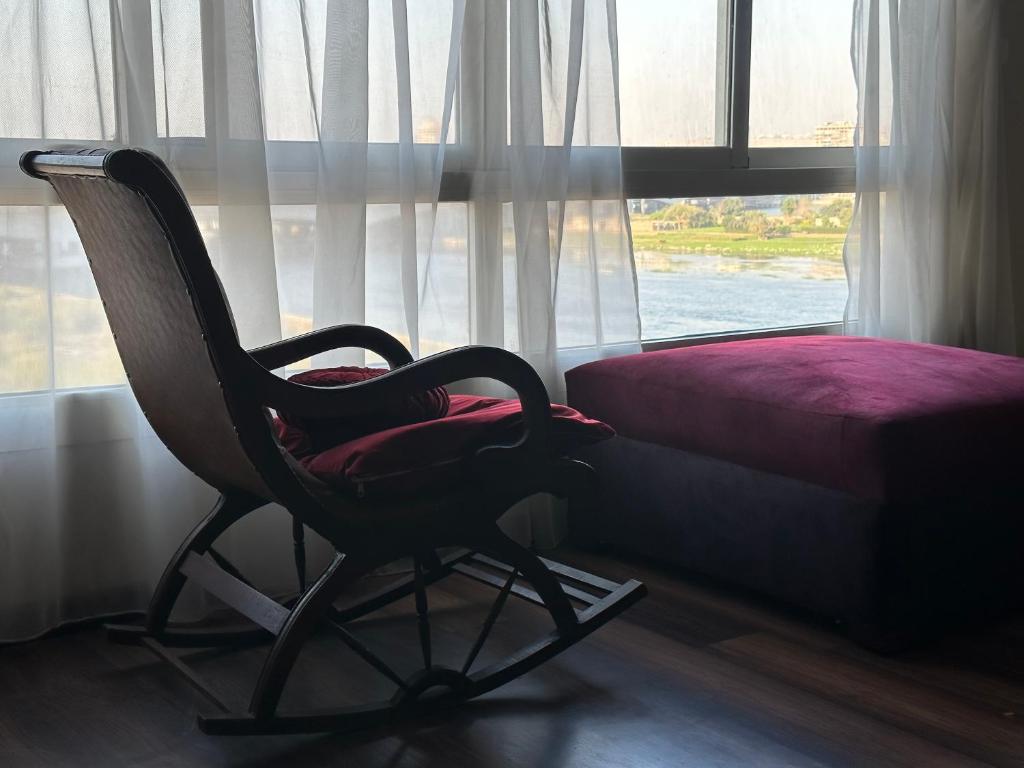 a chair sitting in front of a window next to a bed at شقة فندقية علي النيل للعائلات بالقاهرة in Cairo