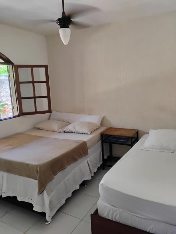 two beds in a room with a window at Casa em Búzios in Búzios