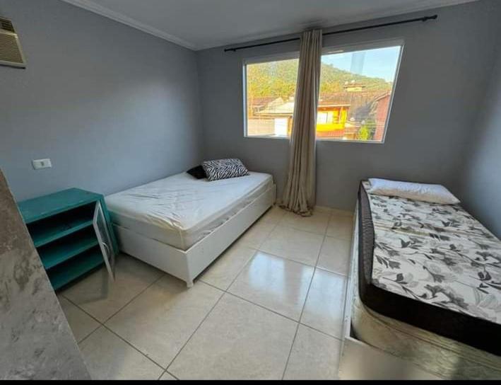 Un dormitorio con dos camas y una ventana. en Suíte família, en São Sebastião