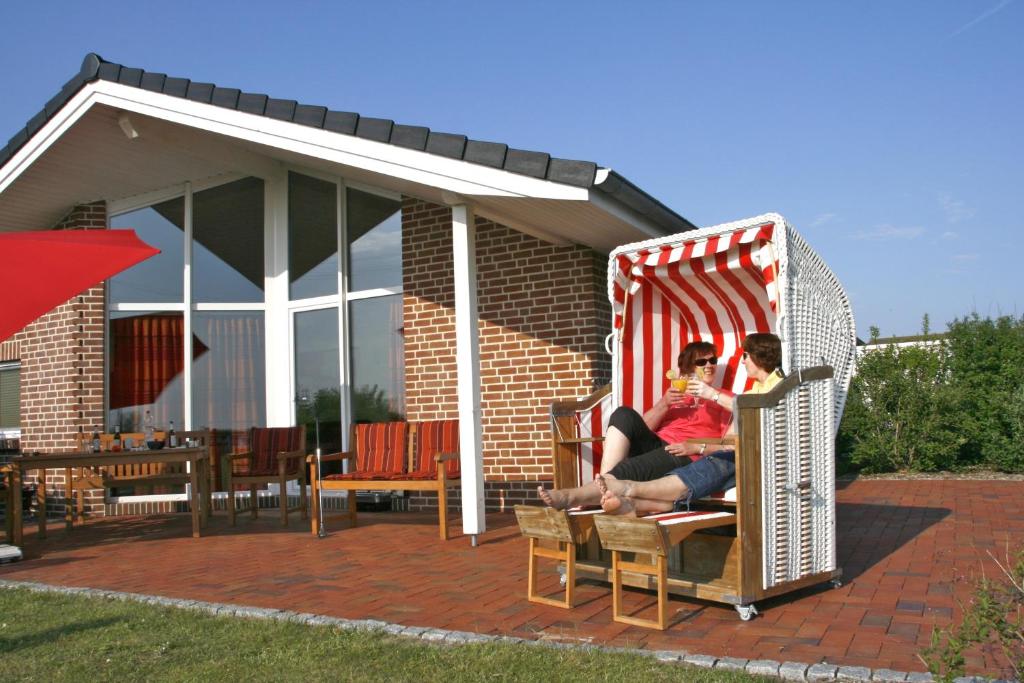 Dos personas sentadas en una silla de mimbre en un patio. en Haus an der Pferdekoppel B, en Fehmarn