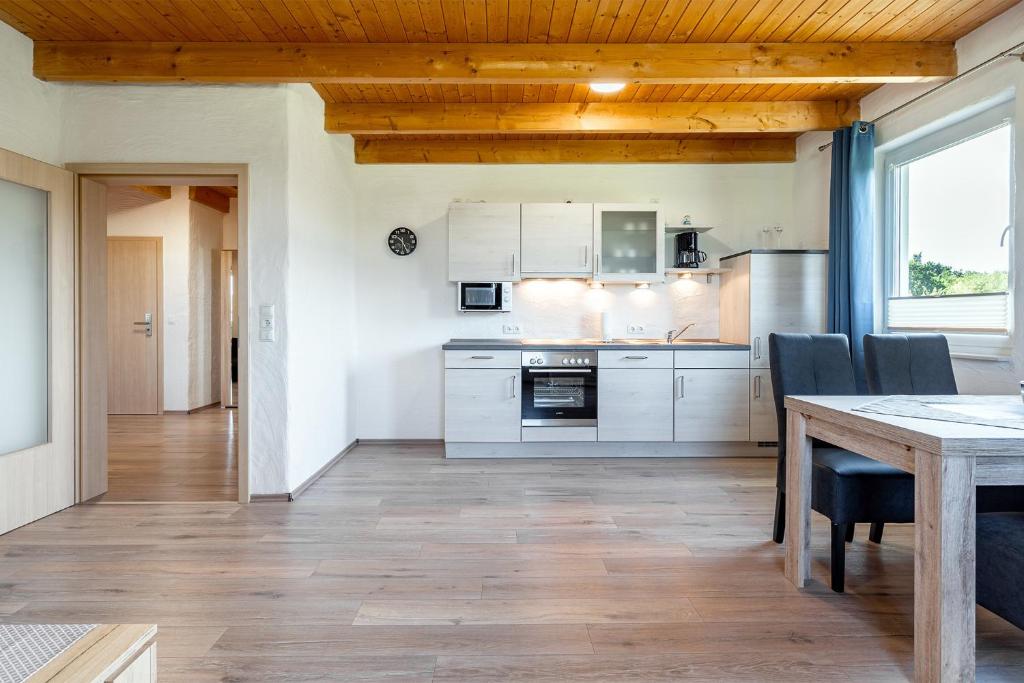 a kitchen with white cabinets and a table and chairs at Ferienwohnung Wattenmeer für 2 Personen am Badesee Tannenhausen in Aurich