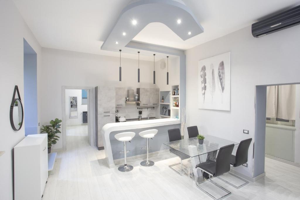 una cucina bianca con tavolo in vetro e sedie di Lounge House Vatican - San Pietro a Roma