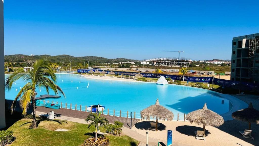 einem großen Pool mit Palmen und einem Gebäude in der Unterkunft Te Va a Encantar, Torre Turquesa in Mazatlán