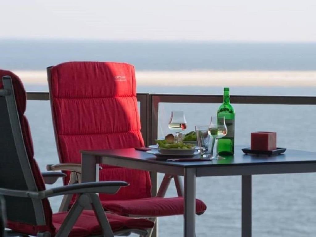 a table with a chair and a bottle of wine at Sea View No 19 Comfortable holiday residence in Wittdün