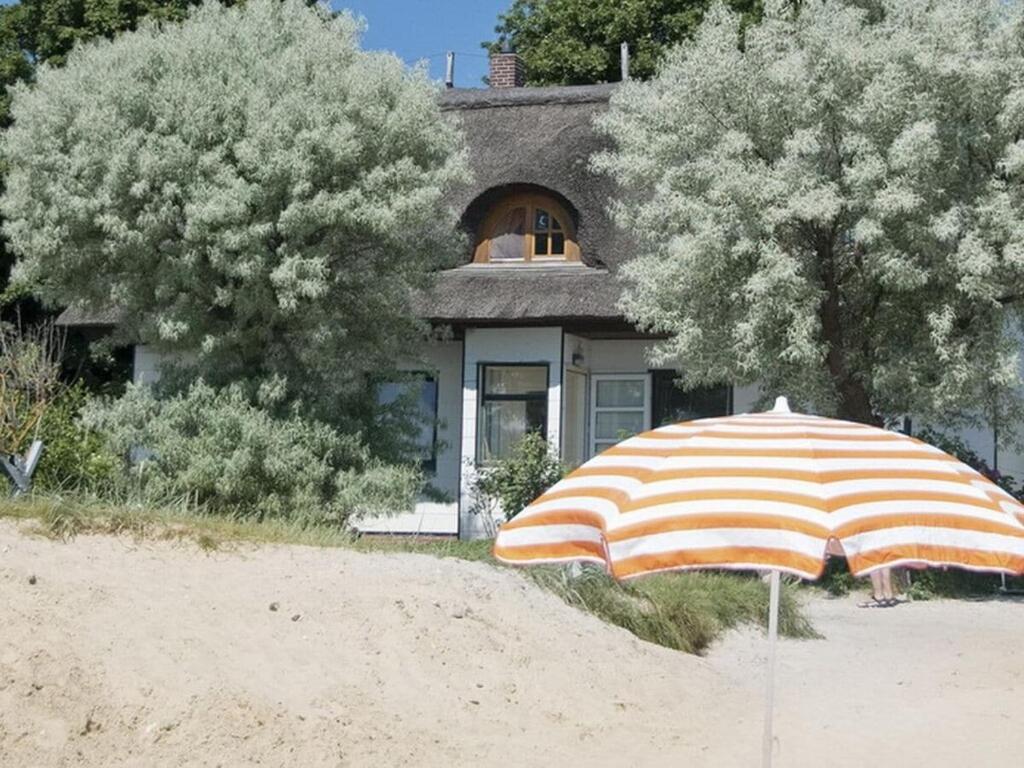 an orange and white striped umbrella in front of a house at Beach house F994 Comfortable holiday residence in Fehmarn