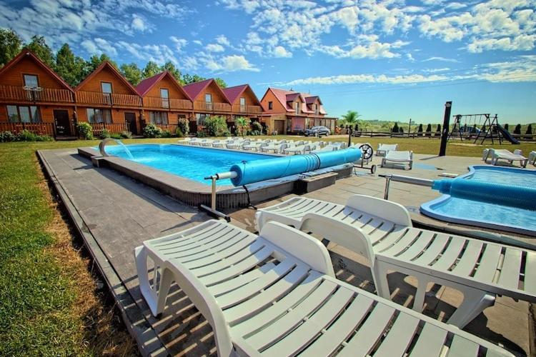 a swimming pool with white lounge chairs and a water slide at Cottage in Jaros awiec near Seaside Beach in Jarosławiec