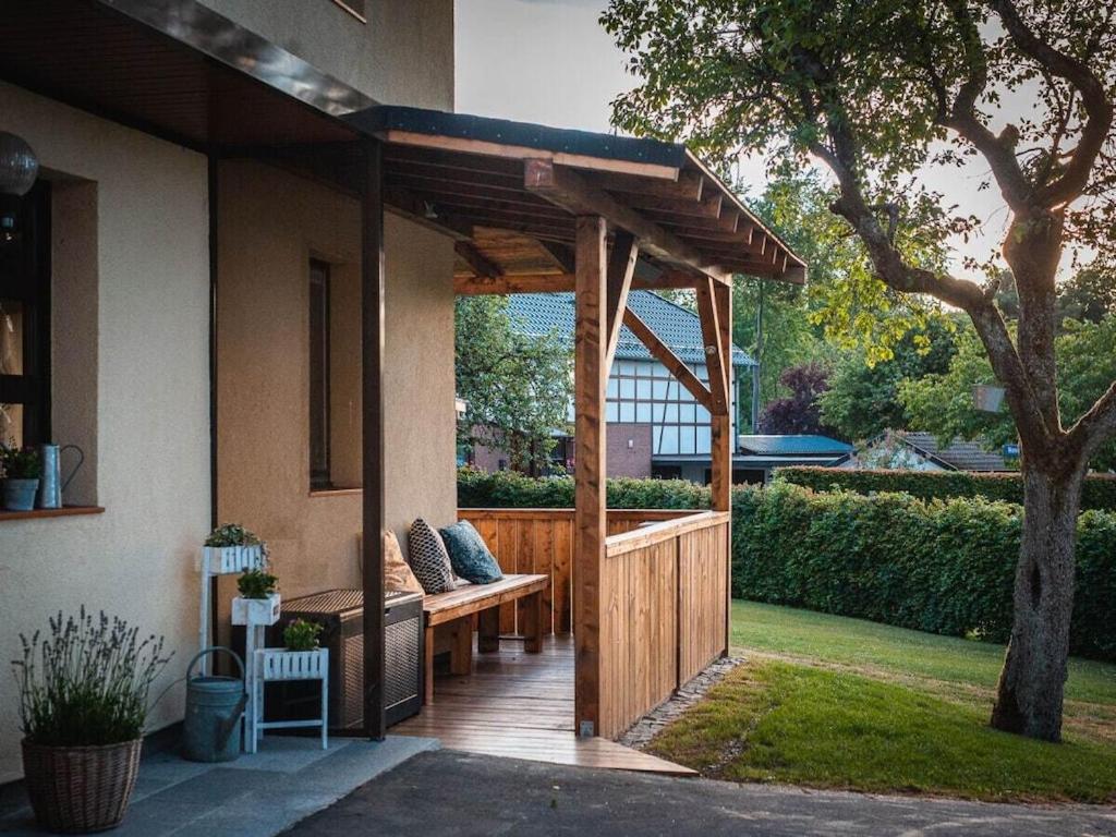 eine hölzerne Pergola mit einer Bank auf einer Terrasse in der Unterkunft Summer house Eifel Comfortable holiday residence in Monschau