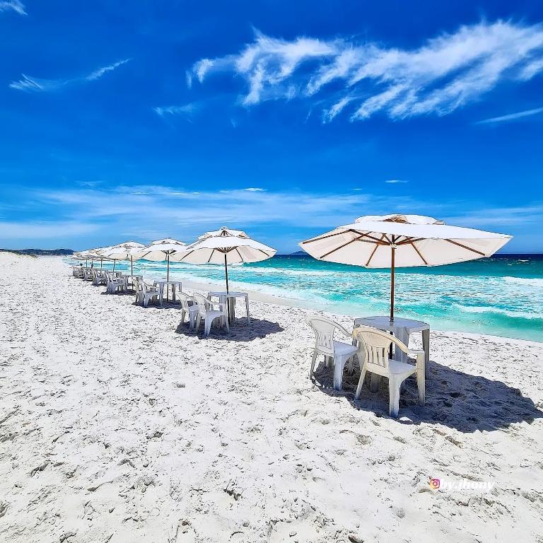 a row of chairs and umbrellas on a beach at Beach House Cabo Frio Hostel in Cabo Frio