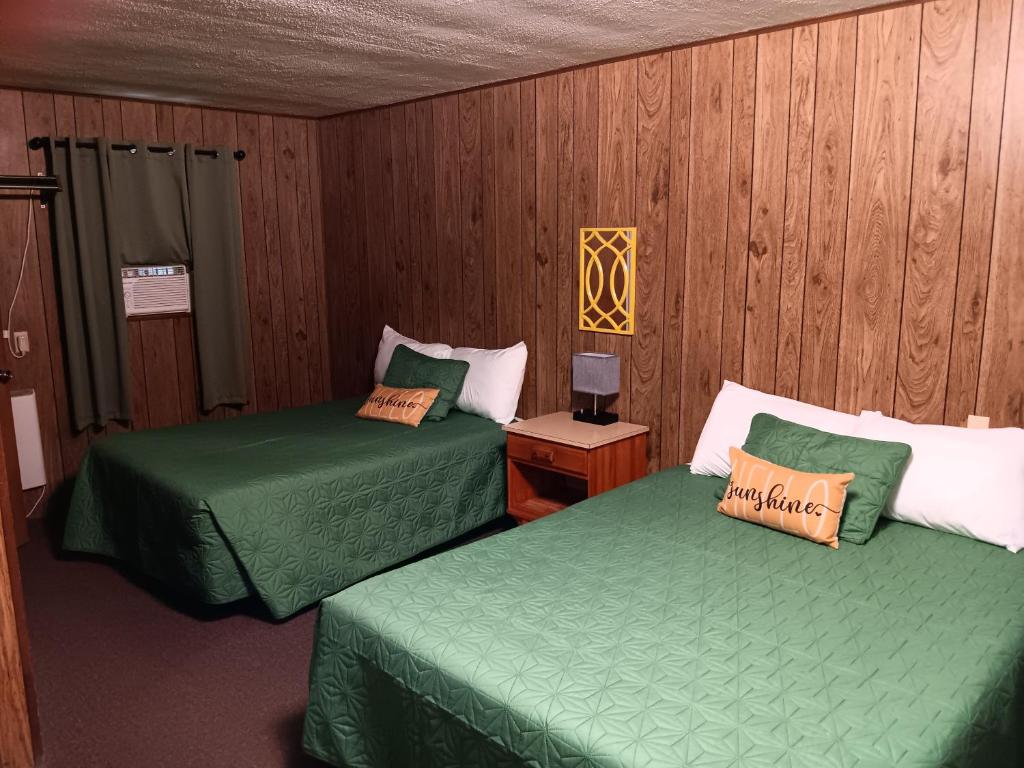 2 letti verdi in una camera con pareti in legno di Crawford Motel a Springfield