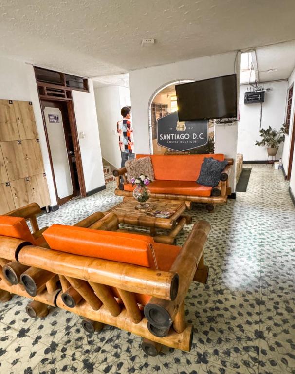 sala de estar con muebles de color naranja y TV en Santiago Dc Hostal 420 weedfriendly, en Cali