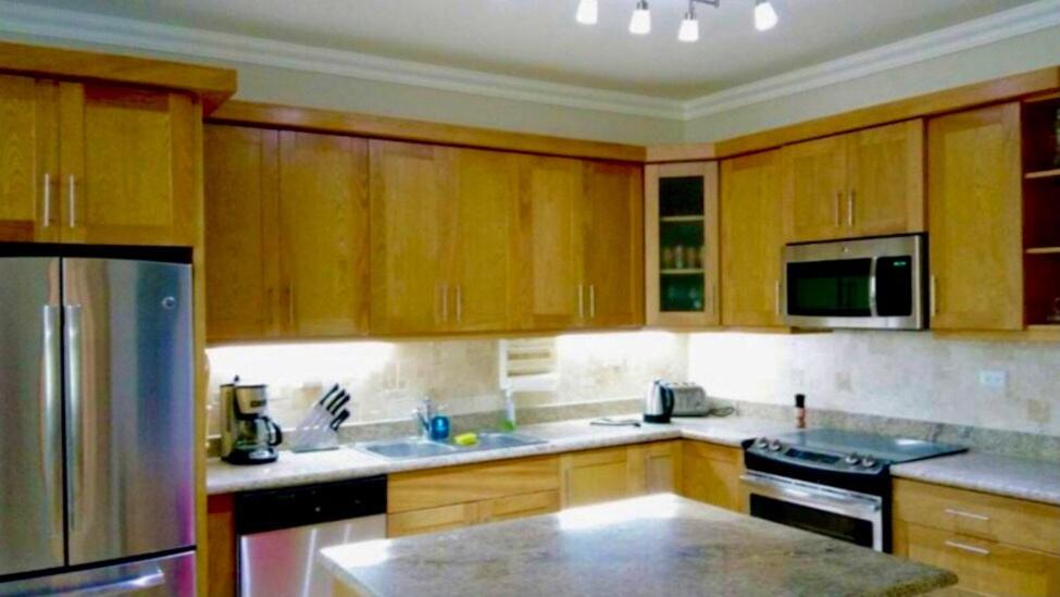 a kitchen with wooden cabinets and stainless steel appliances at Hispañola Beach Beautiful condo with private beach two bedrooms in Sosúa