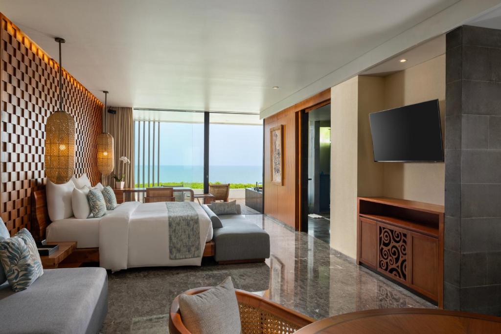 a hotel room with a bed and a television at Anantara Uluwatu Bali Resort in Uluwatu