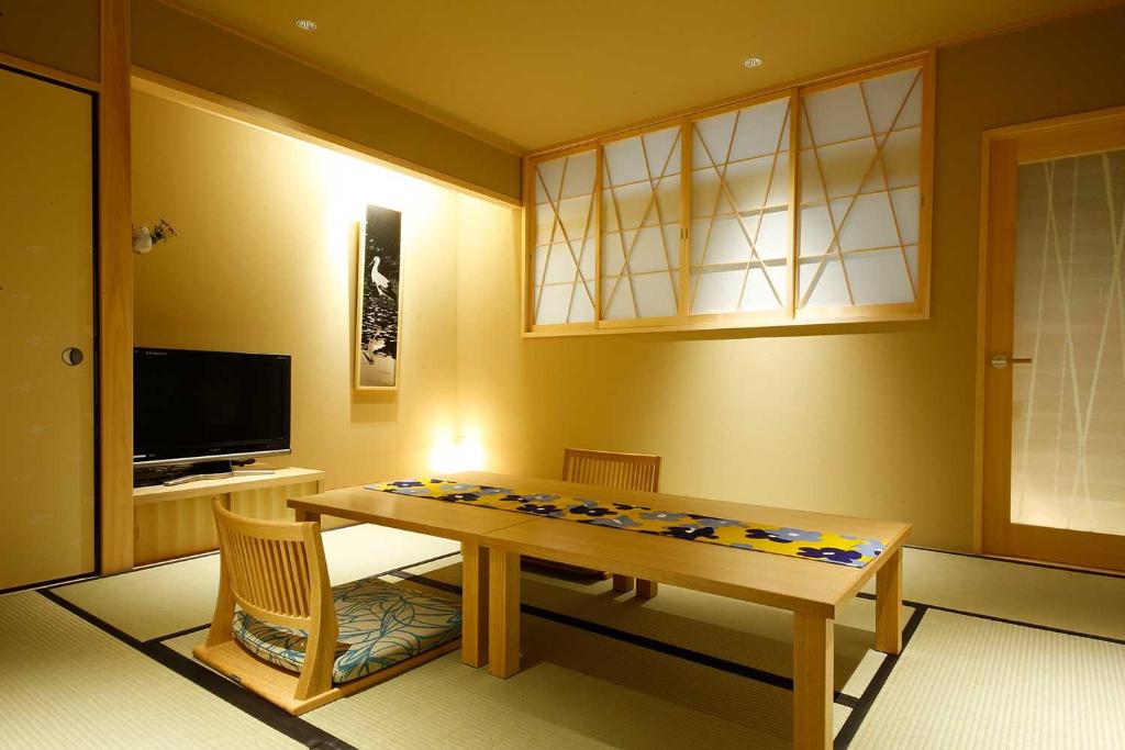 a dining room with a table and a television at Yuraku Kinosaki Spa & Gardens in Toyooka