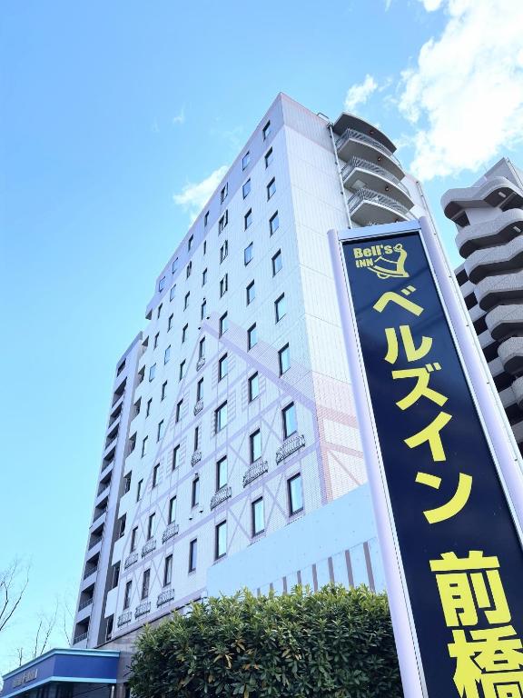 a tall building with a sign in front of it at Bell's Inn Maebashi in Maebashi