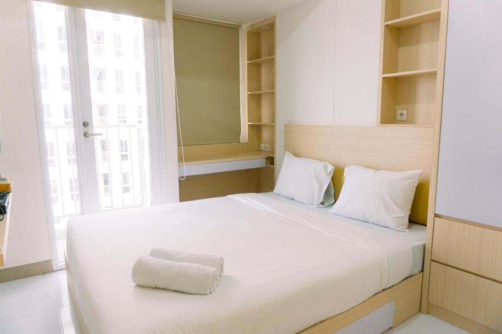 a bedroom with a white bed with a towel on it at New and Nice Designed Studio at Tokyo Riverside PIK 2 Apartment By Travelio in Rawalembang