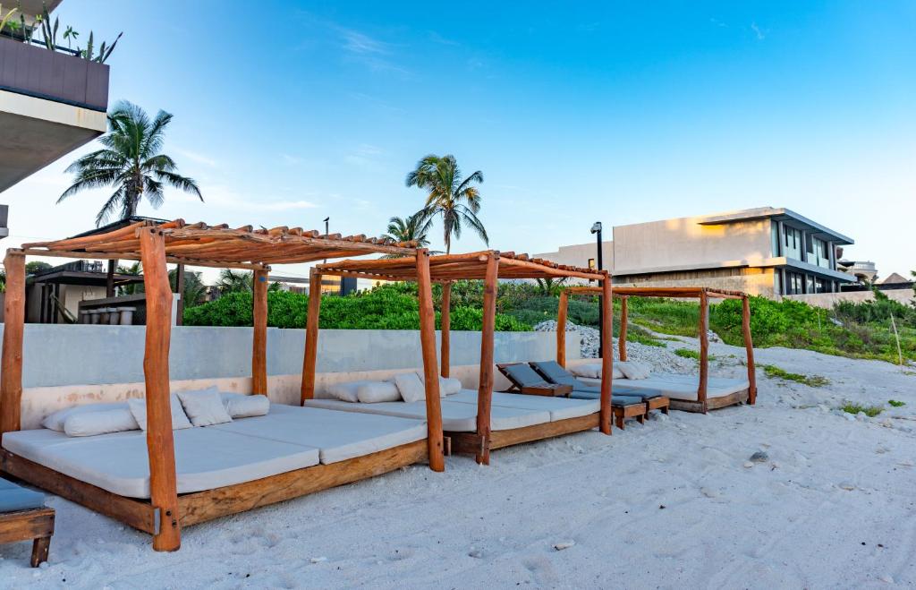a group of beds sitting on the beach at Luxury Romantic Getaway - 1 Bedroom - Steps from the Beach - Bahia Tankah Tulum in Tulum