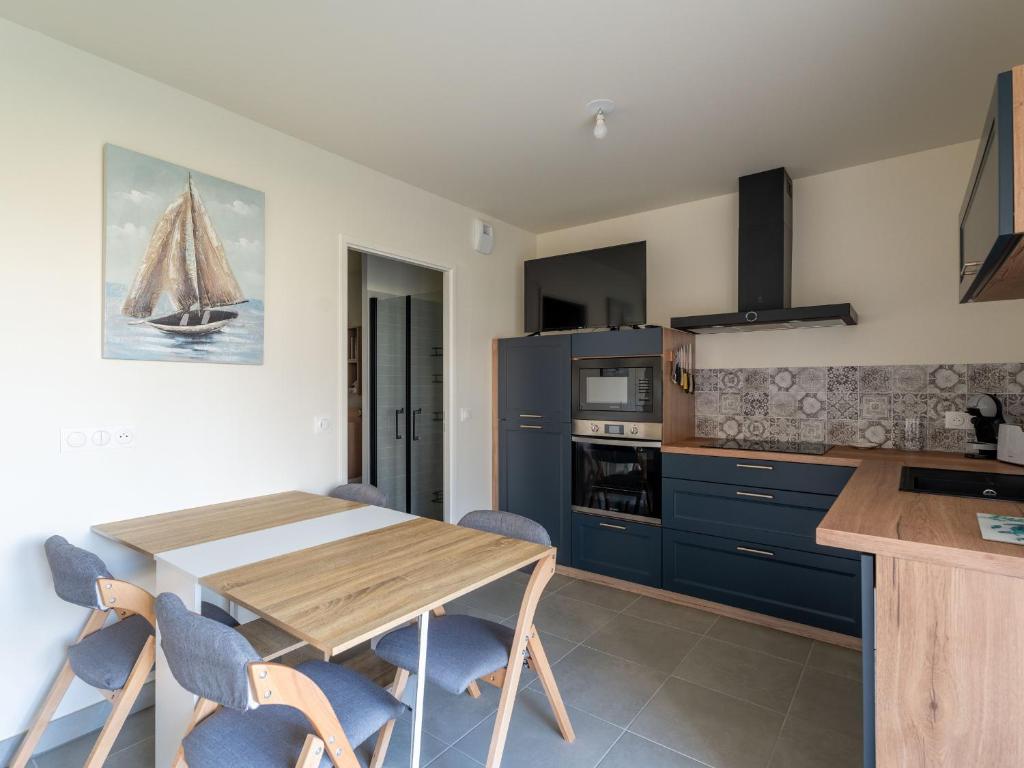 une cuisine avec une table en bois et des armoires bleues dans l'établissement Appartement moderne à Mimizan Plage, proche de l'océan, pour 6 pers, terrasse est - FR-1-50-159, à Mimizan