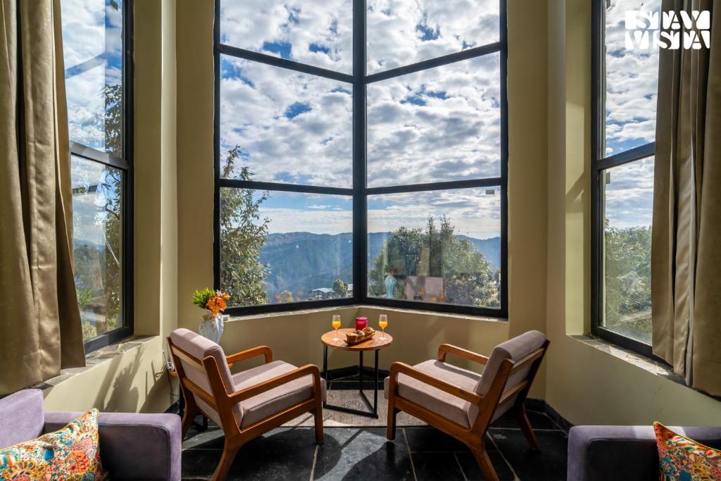 a room with a table and chairs and large windows at StayVista at Villa Vienna with Lawn & Bonfire in Mukteswar
