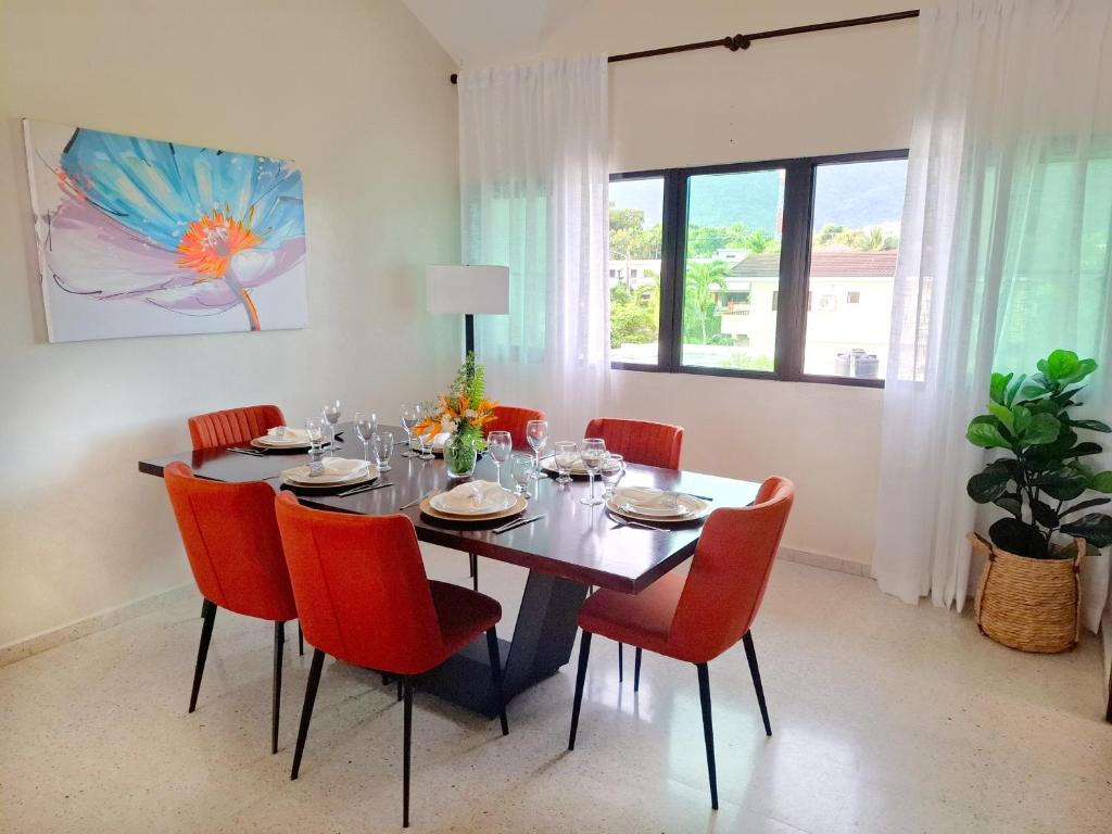een eetkamer met een tafel en rode stoelen bij Bright & Modern Apartment in Puerto Plata, Secure, and Central! in San Felipe de Puerto Plata