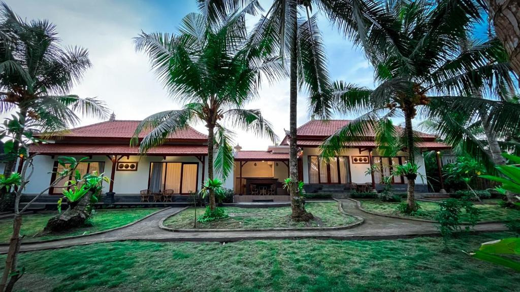 a house with palm trees in front of it at Pondok Kakiang in Pulukan
