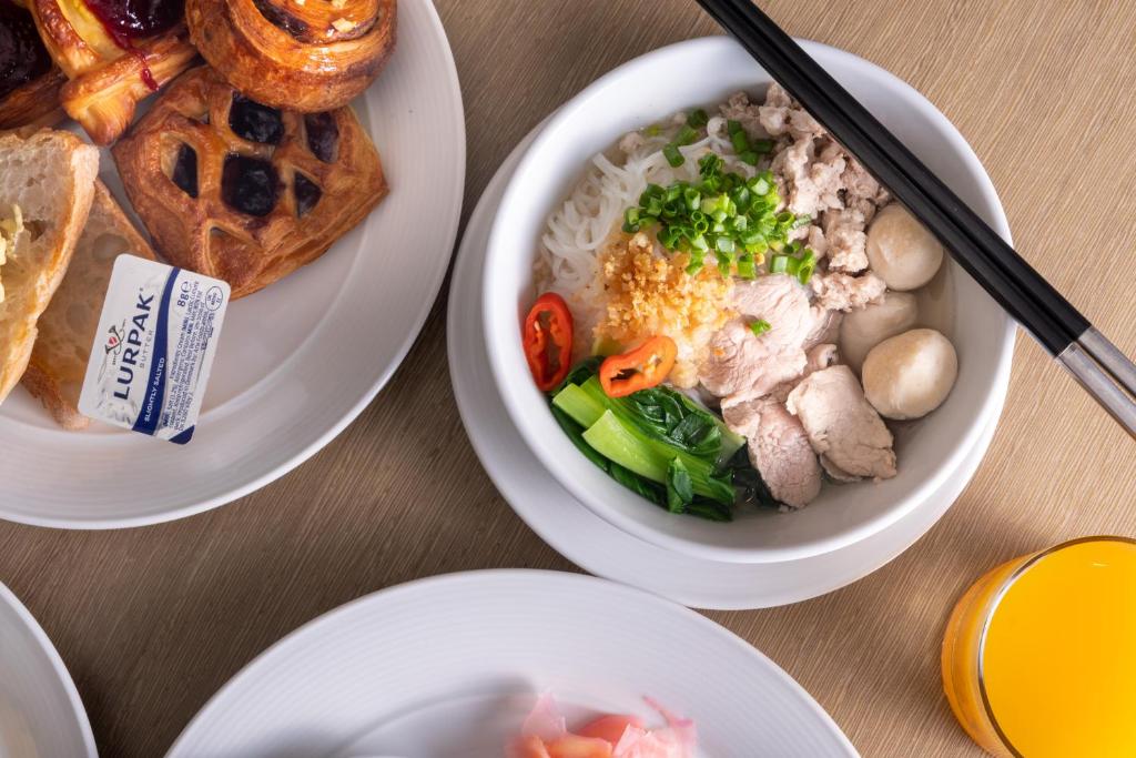 A breakfast table combining noodle soup, pastries and a cold drink.