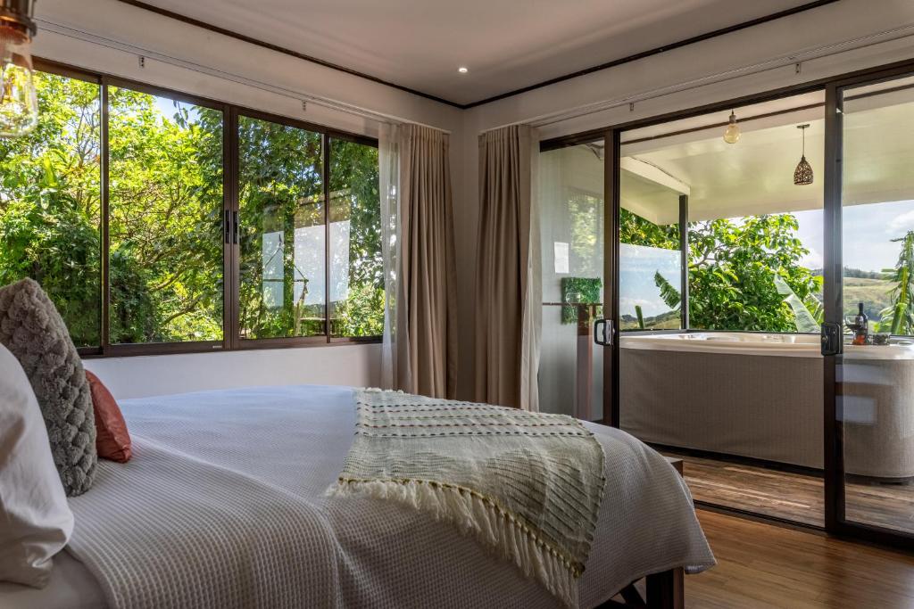a bedroom with a bed and large windows and a tub at Villa Alma de Campo Monteverde in Monteverde Costa Rica
