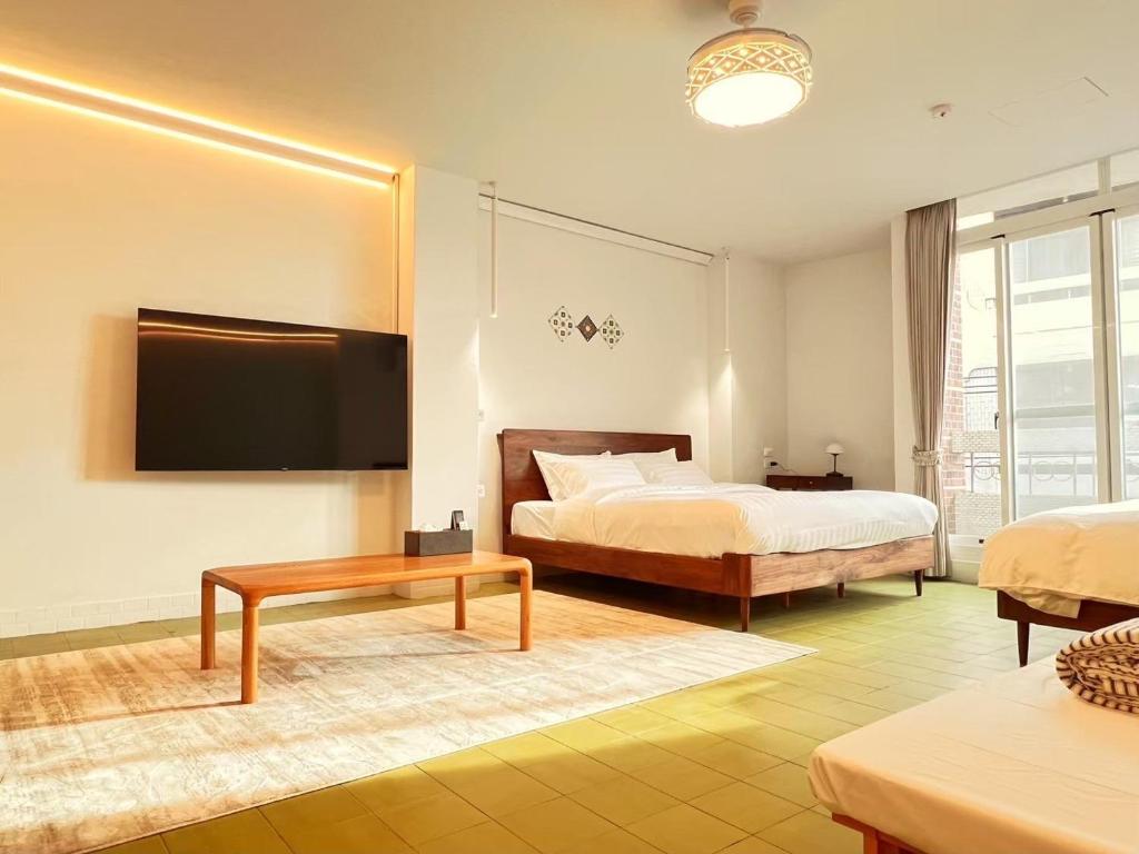 a bedroom with two beds and a flat screen tv at 壹貳貳洋樓 l 自助入住 l 無人櫃檯 in Chiayi City
