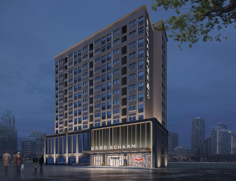 a large hotel building with people standing in front of it at Echarm Hotel Changsha Huanghua Airport in Changsha