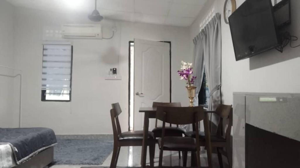 a room with a table and chairs and a bedroom at D'Orkid Homestay Kebun baru in Teluk Panglima Garang