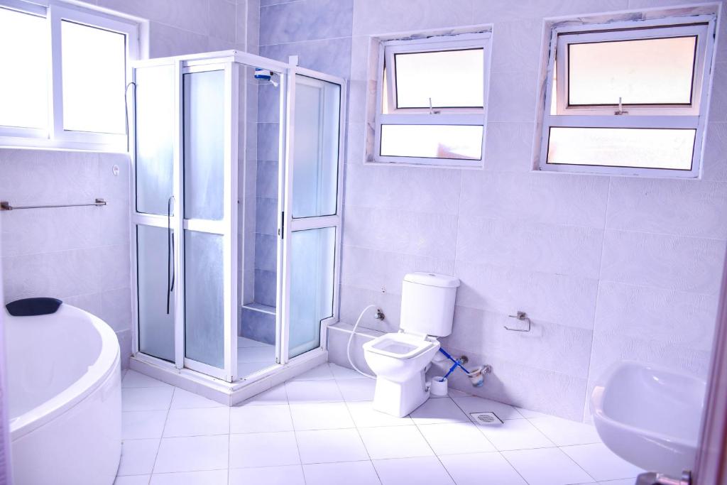 Un baño blanco con ducha y WC. en Iko homes, en Mombasa