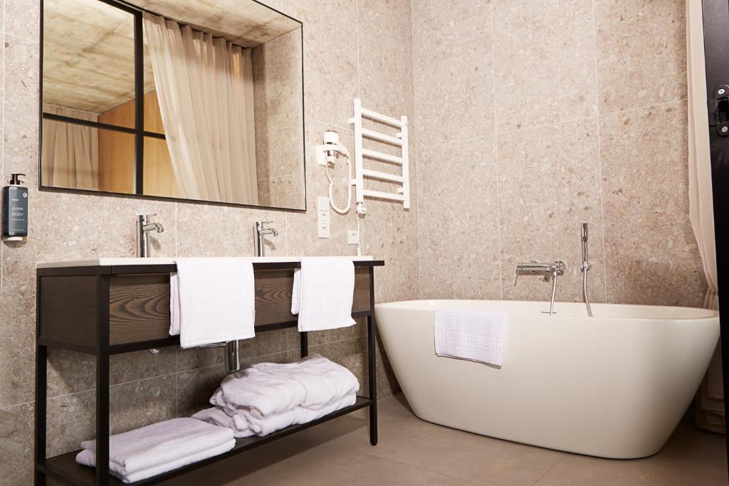 a bathroom with a tub and a sink and towels at Air Hotel in Karmėlava