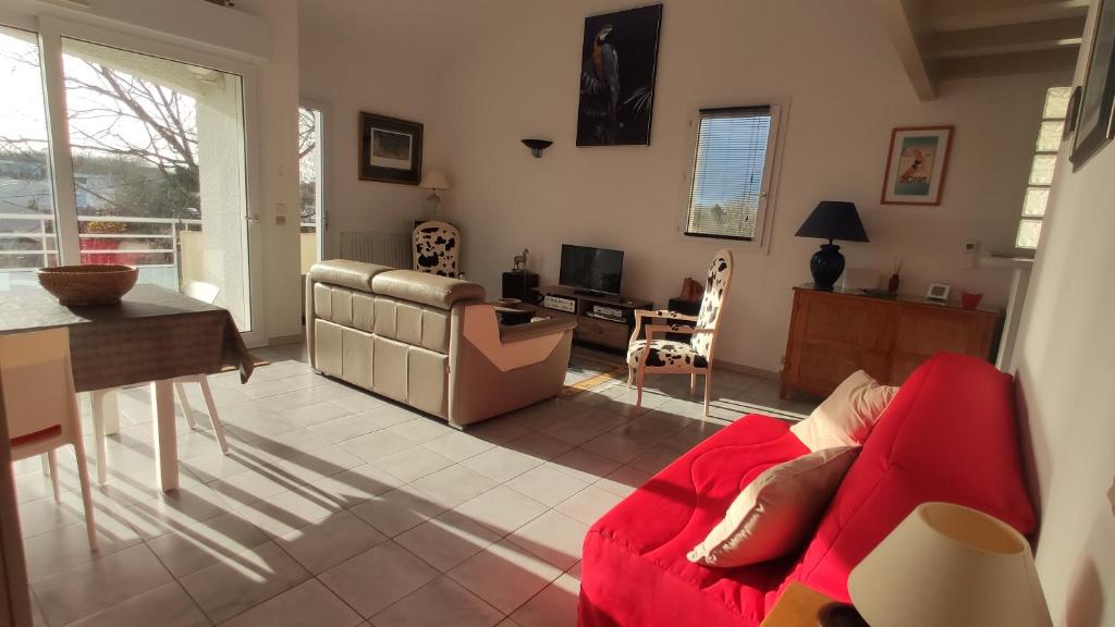 a living room with a red couch and a table at La Vague de Pontaillac 55m2 in Royan