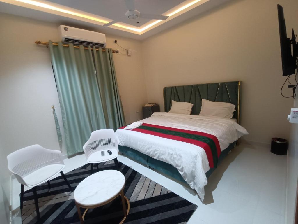 a bedroom with a bed and two white chairs at نستو للشقق الفندقية in Fūwah