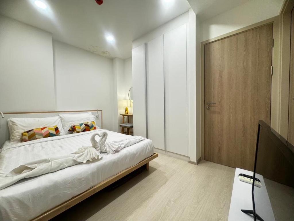 a white bedroom with a bed and a television at Ekamai 2 bed room in Khlong Toei