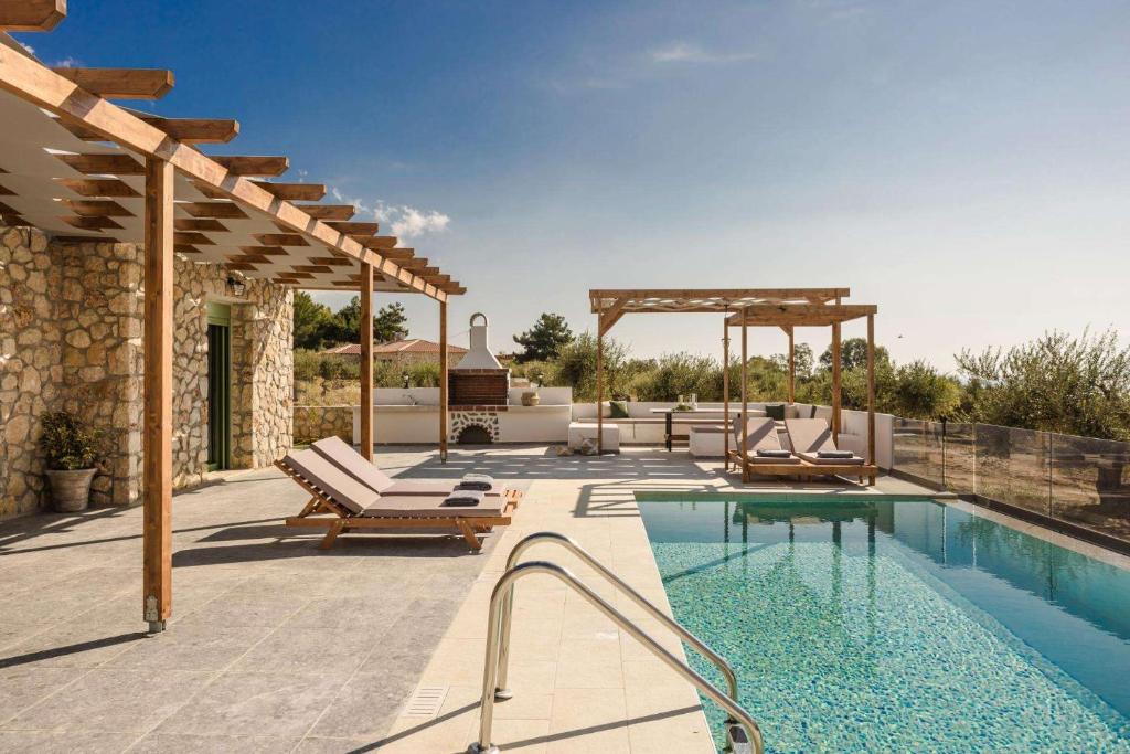 a patio with a swimming pool and a house at Athina Villa by Vintage Travel in Karavádhos