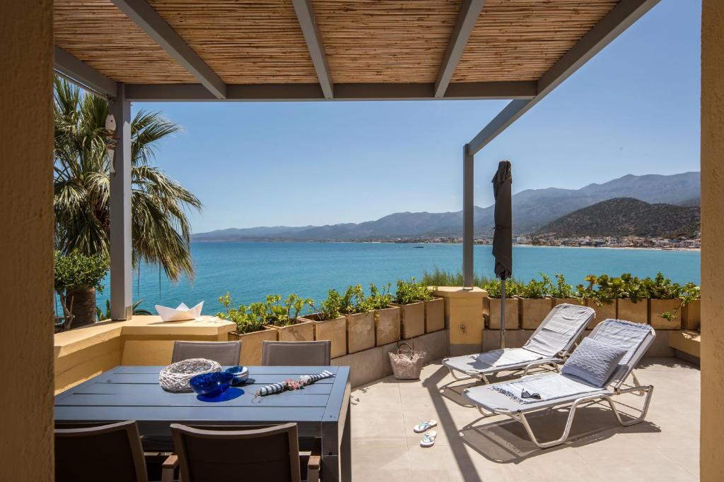 a patio with a table and chairs and a view of the water at Skajado Holiday Apartments in Stalís