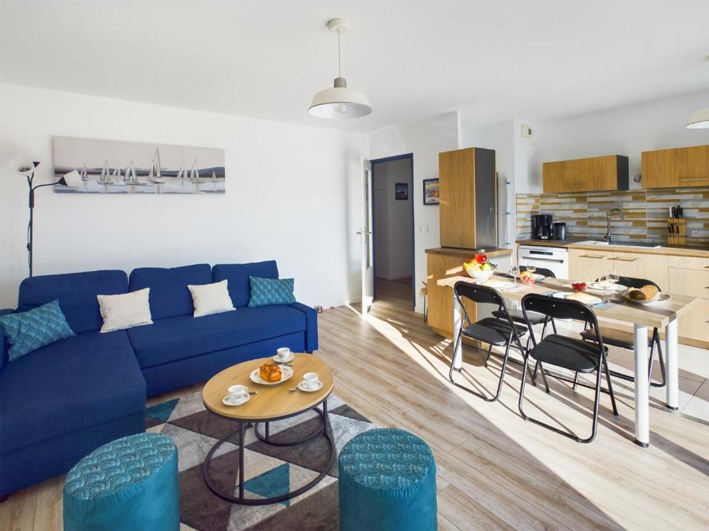 un salon avec un canapé bleu et une table dans l'établissement -INDIGO-T3 avec balcon et 2 places de parking, à Concarneau