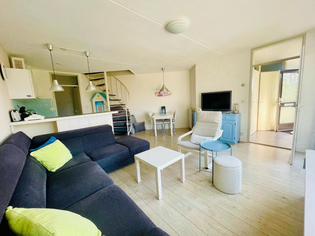 a living room with a blue couch and a table at Liguster 51* in Nieuwvliet
