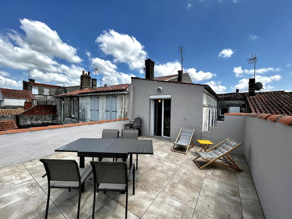 un patio avec une table et des chaises sur un toit dans l'établissement La Salamandre - Situé en plein coeur de ville et proche des thermes, à Rochefort