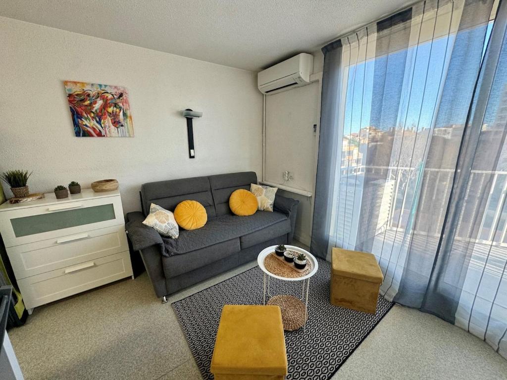 un salon avec un canapé et une fenêtre dans l'établissement Appartement - Cap d'Agde, au Cap d'Agde