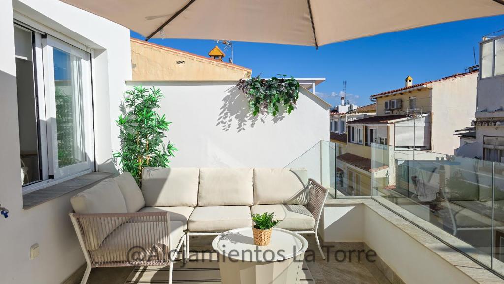 a balcony with a couch and an umbrella at Atico Melosas - Alojamientos La Torre in Torre del Mar