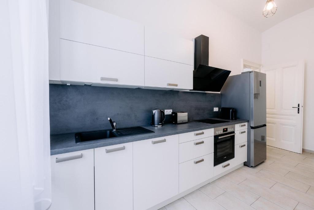 a white kitchen with a sink and a refrigerator at Elegant Vienna Apartment in Vienna