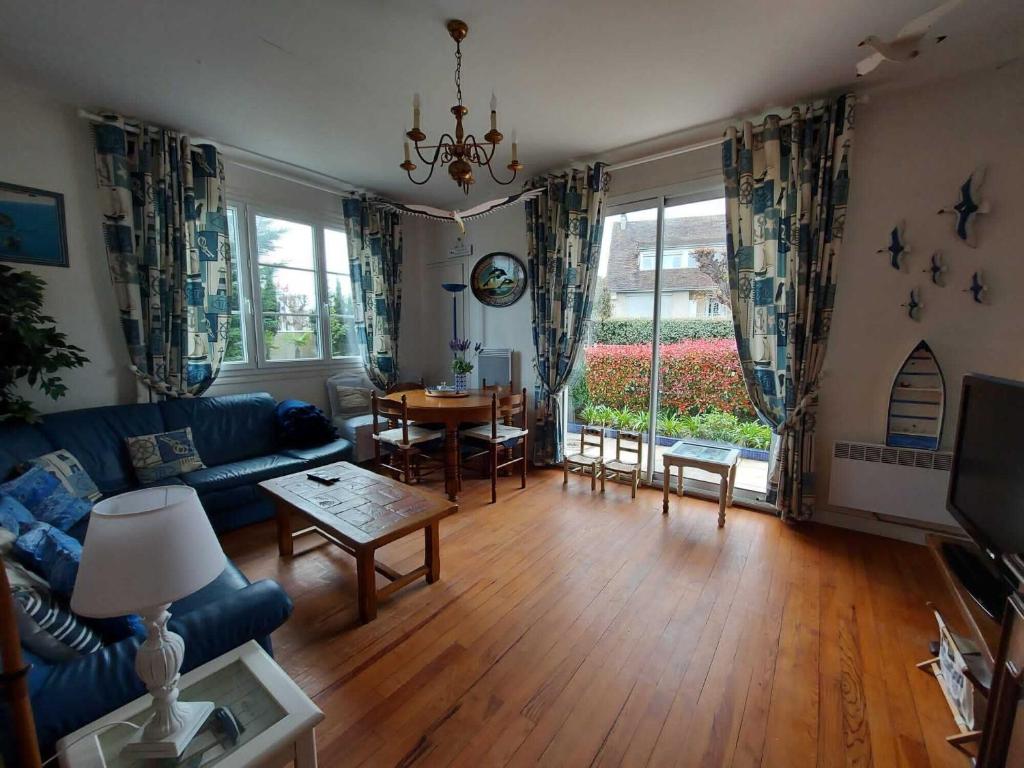 un salon avec un canapé bleu et une table dans l'établissement Maison Familiale Proche mer, à Ouistreham