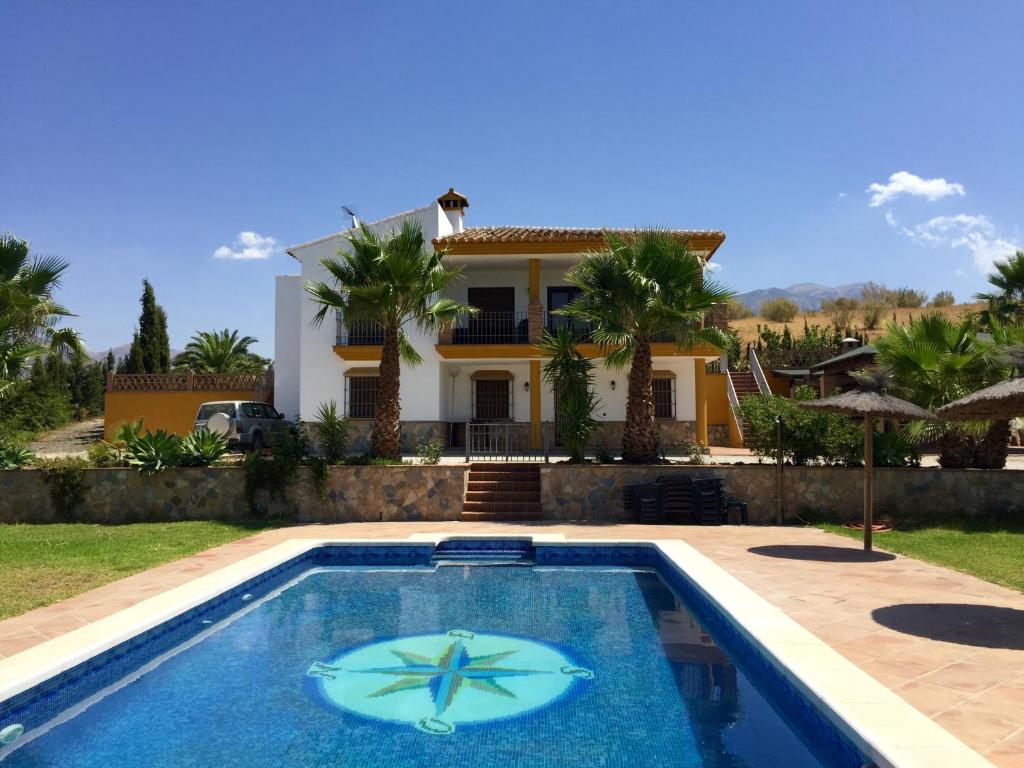 a villa with a swimming pool in front of a house at La Solana De Domingo in Viñuela