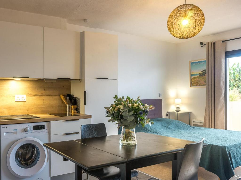 une cuisine avec une table avec un vase de fleurs dessus dans l'établissement Studio à Larmor-Plage: balcon, parking, à 500m de la mer et des commerces - FR-1-349-110, à Larmor-Plage