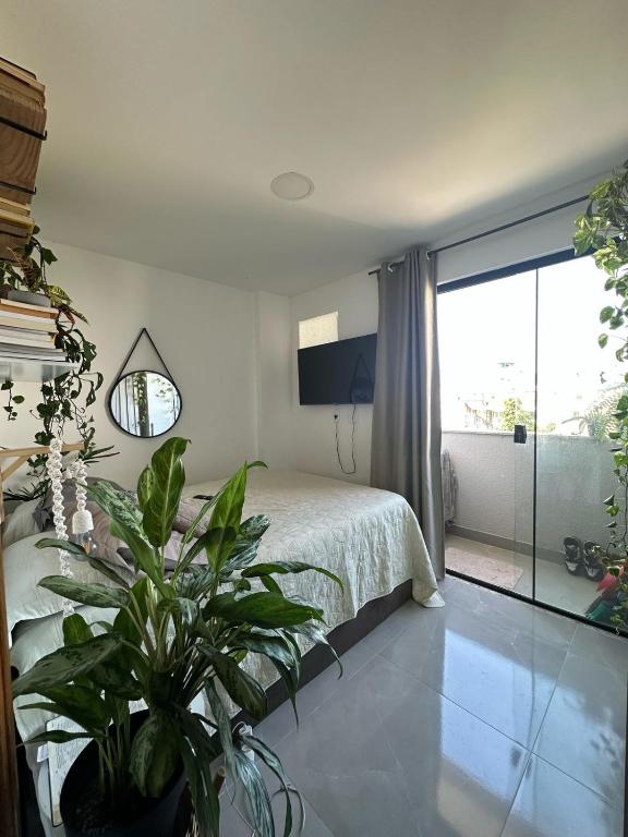 Un dormitorio con una cama y una planta en maceta. en Lindo apartamento - 3 min da praia do recreio, en Río de Janeiro