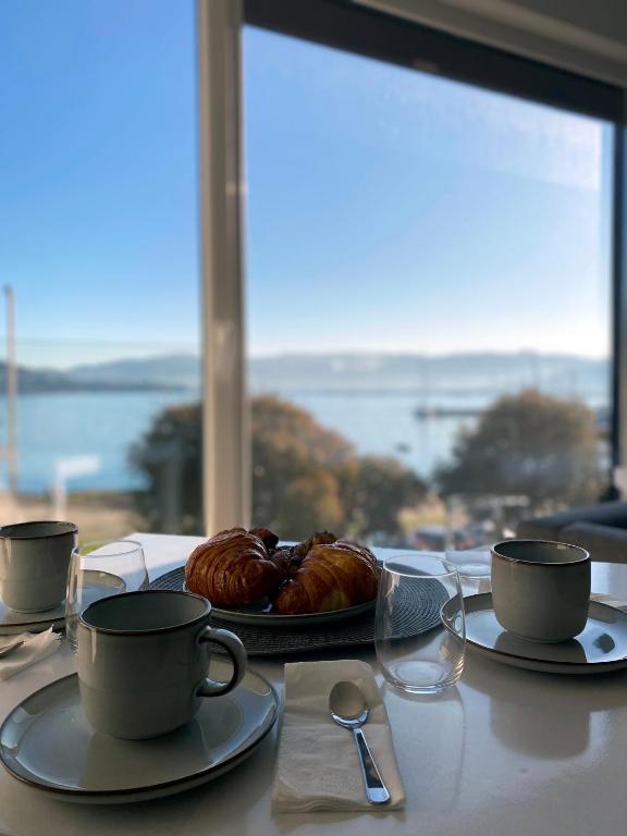 a table with two cups and a plate of pastries at Alojamientos Ría de Vigo & Alborada in Moaña