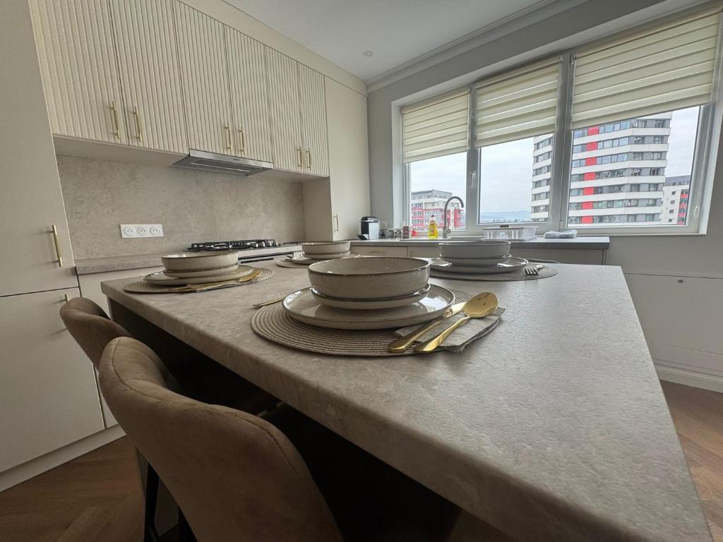 a kitchen with a table with plates and utensils on it at High Stay Suite Cluj in Floreşti